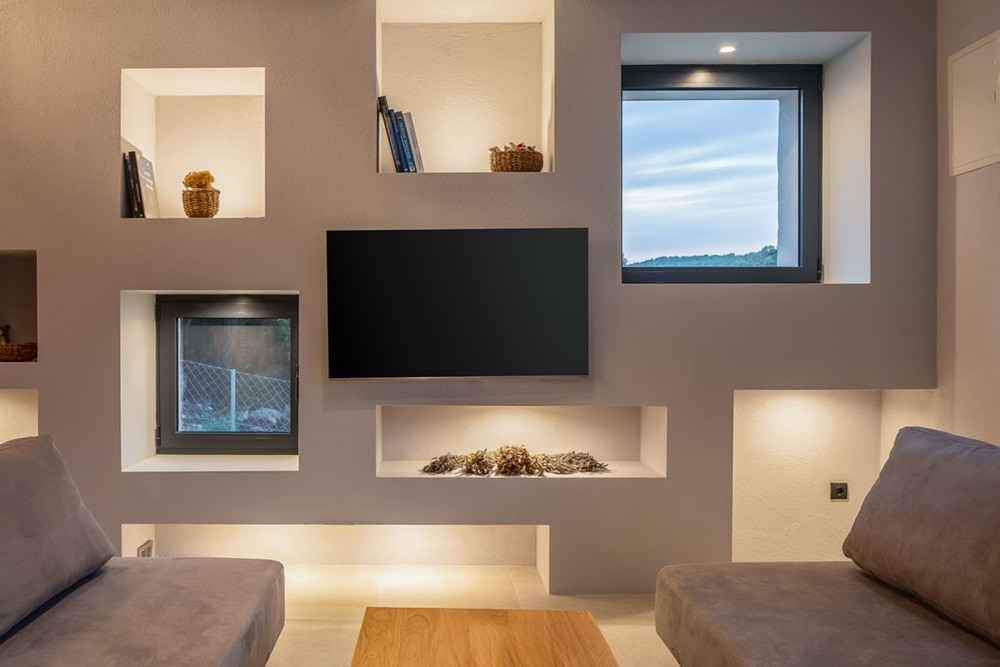 Hager group Salon design avec mur et étagères en béton éclairés et deux fenêtres