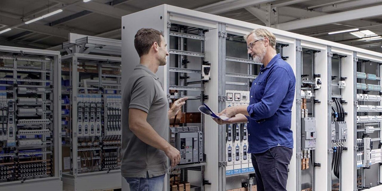hager employees standing infront of a hager switchboard
