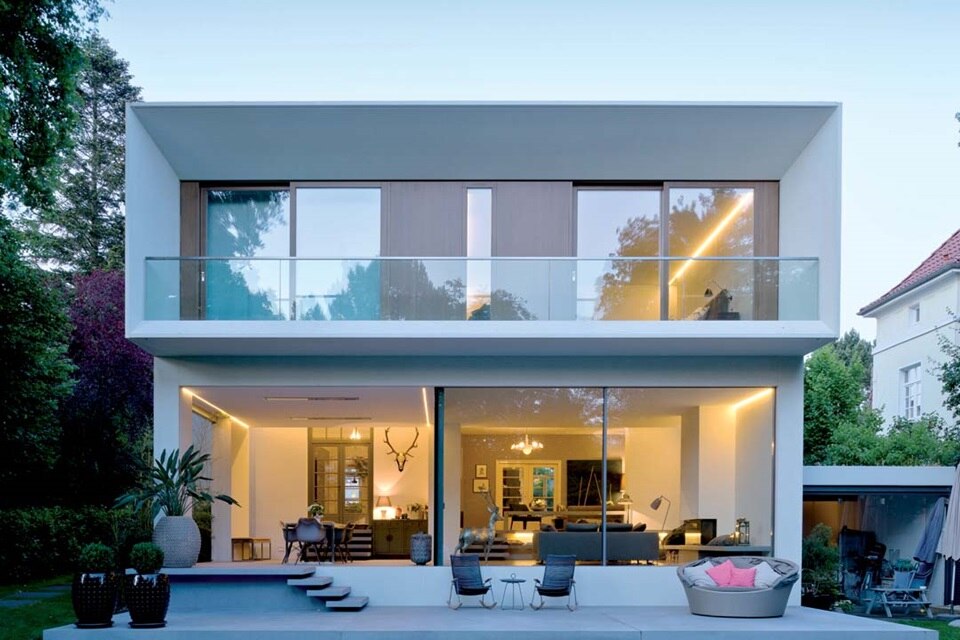 Modern house facade with balcony and outdoor lighting at dusk
