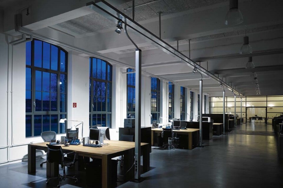 Espace de bureau moderne avec éclairage sur rail et postes de travail au crépuscule