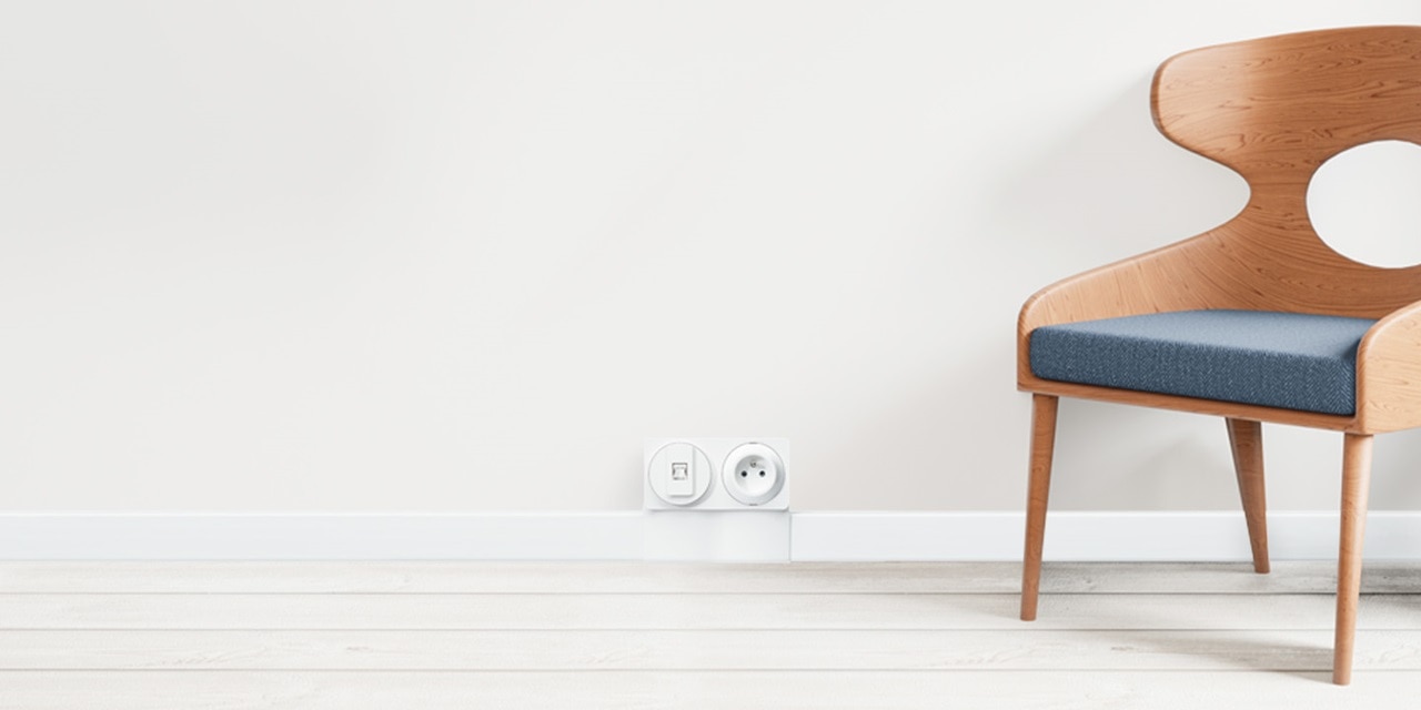 Intérieur minimaliste avec une chaise moderne en bois et un mur comportant une prise électrique et un interrupteur