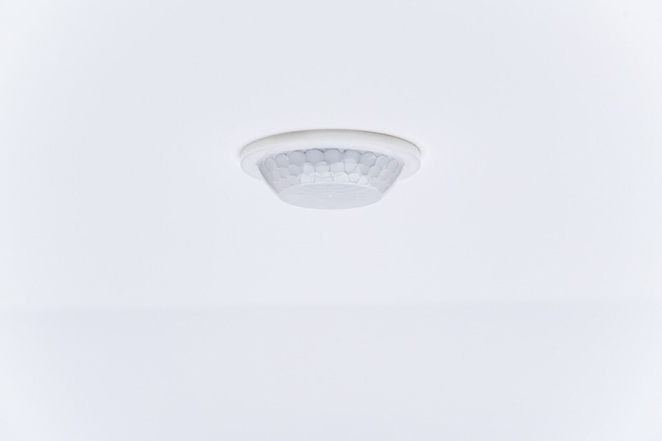 Détecteur de fumée monté au plafond dans une pièce blanche