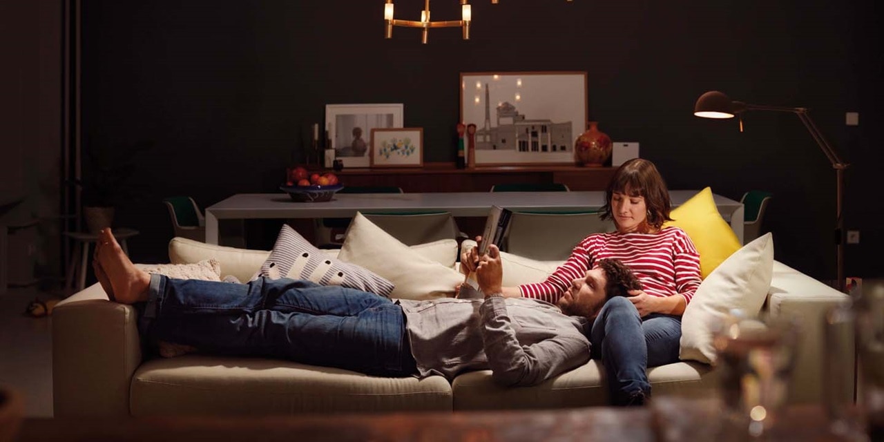 Deux personnes se détendant sur un canapé dans un salon cosy avec un éclairage moderne