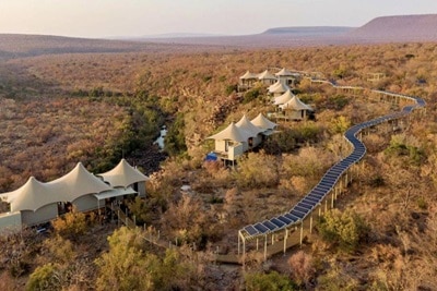 Tentes de toile de luxe d'un lodge de safari avec la nature environnante et une allée bordée de panneaux solaires