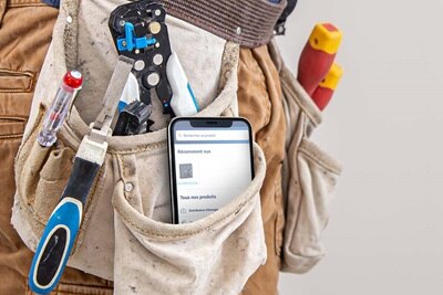 Ceinture d'outils d'électricien avec coupe-câble, tournevis et smartphone affichant des produits électriques