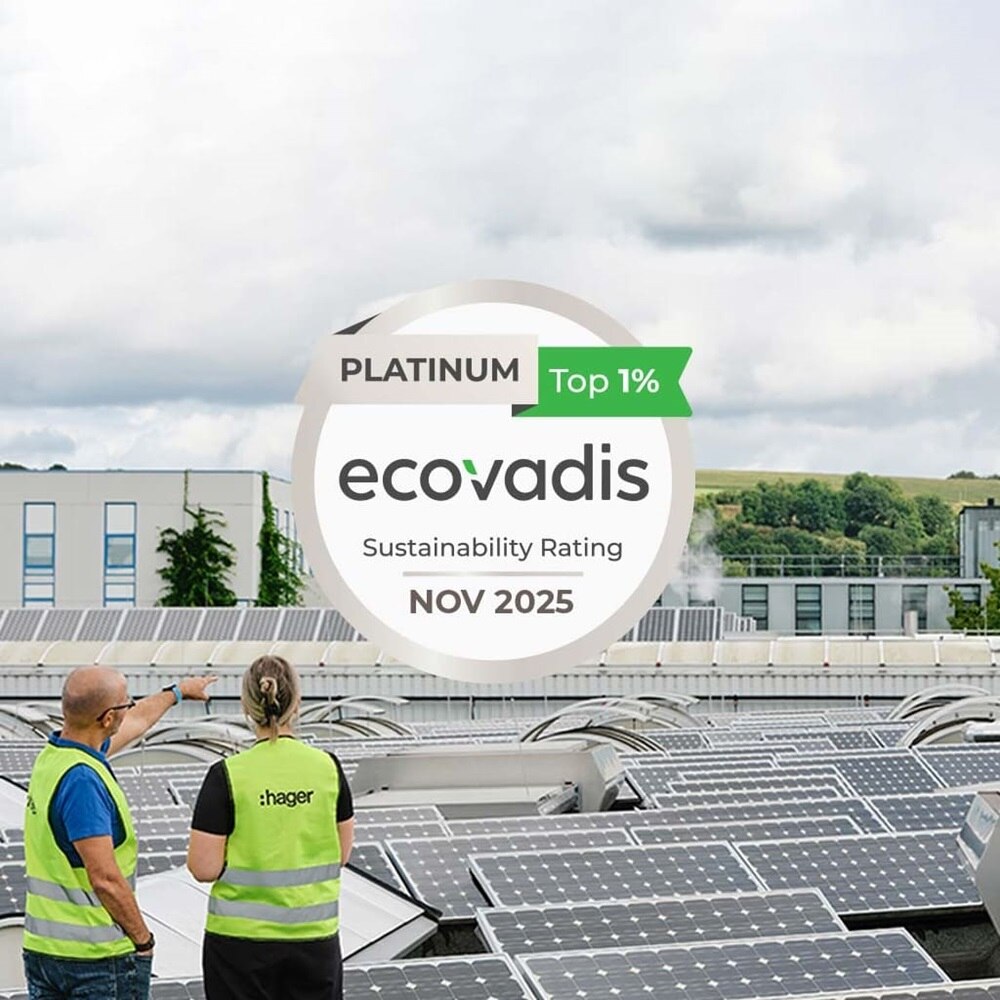 Uomo e donna sulla sinistra con giubbotto di emergenza catarifrangente su un tetto di una fabbrica munito di pannelli fotovoltaici osservano il cielo in direzione del logo che attesta la certificazione ecovadis platinum novembre 2025