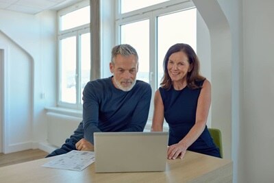 Uomo e donna seduti ad un tavolo intenti a guardare un notebook 