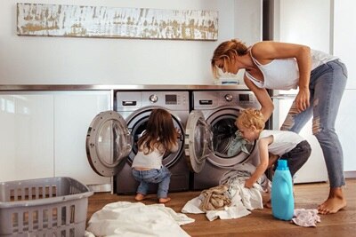 Esempio di applicazione degli interruttori tipo F: una mamma e due bambini sono intenti a caricare la lavatrice nel locale lavanderia di casa.
