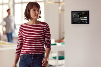 Donna si dirige verso il tablet di controllo sul muro per la gestione della sua casa