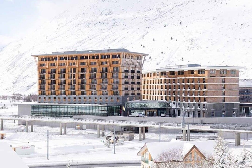 Esterno del Radisson Blu Hotel Reussen ad Andermatt, Svizzera, con facciata moderna e paesaggio montano sullo sfondo.