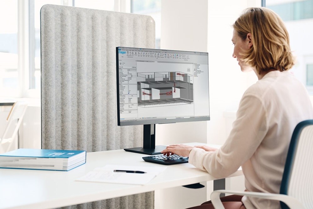 Donna seduta di spalle alla scrivania mentre utilizza un software di progettazione BIM (Building Information Modeling) su un computer.