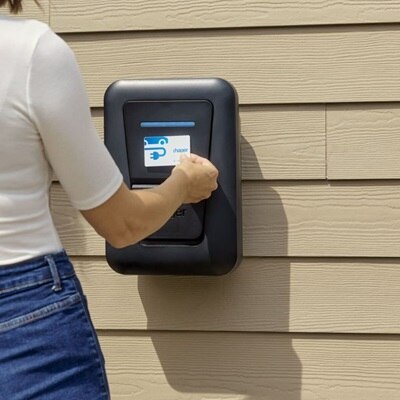 Un installatore utilizza la colonnina di ricarica witty one con cavo, installata nella parete esterna di una casa, avvicinando la carta RFID per attivare la ricarica.