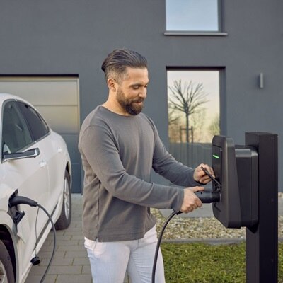 Uomo collega il cavo di ricarica alla colonnina witty plus nel parcheggio di casa.