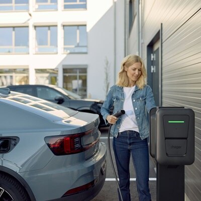 Ragazza collega il cavo di ricarica alla colonnina Witty Pro in un parcheggio aziendale.