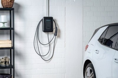 Colonnina witty one Hager con frontalino nero montata a parete all'interno di un garage residenziale.