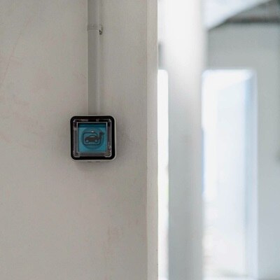 Vista frontale della presa di ricarica witty prise montata su una parete bianca parete all’interno di un garage o parcheggio condominiale.