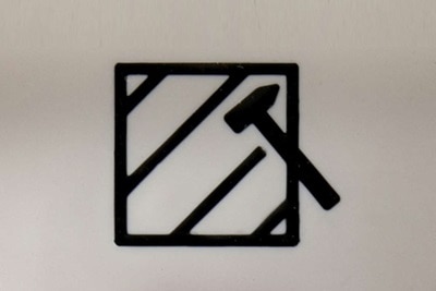 Dettaglio della pittografia martello rottura vetro posto sopra il pulsante rosso illuminabile del centralino di emergenza Pablo IP55 CE PULS R.