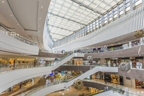 Vista di un centro commerciale con ampia vetrata come soffitto e scale mobili
