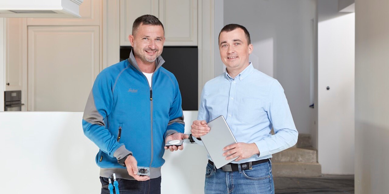 Elettricista e progettista all'interno di una casa discutono sui punti luce Berker da installare nel progetto residenziale