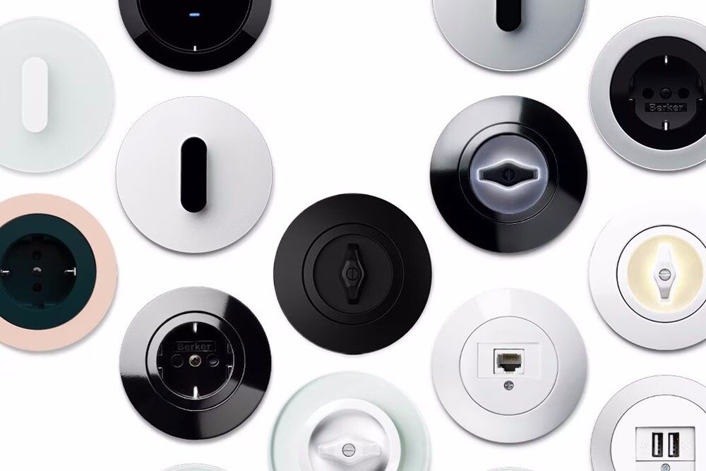 Diversi modelli e finiture di interruttori e prese Berker di forma rotonda su sfondo bianco 