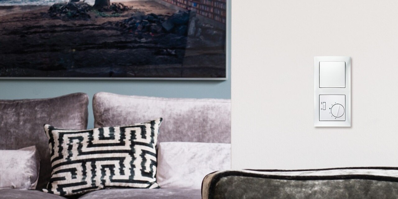 Esempio di installazione dell'interruttore della luce Berker R.3 e del regolatore della temperatura ambiente con cornice bianca su una parete bianca in camera da letto