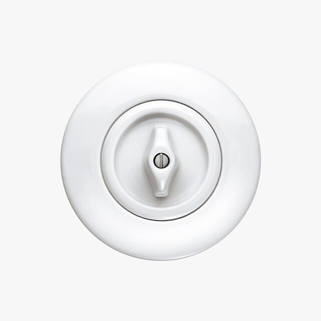 Vista frontale dell'interruttore Berker Serie 1930 con interruttore rotativo montato all’interno della cornice rotonda, entrambi in porcellana bianca su sfondo neutro grigio