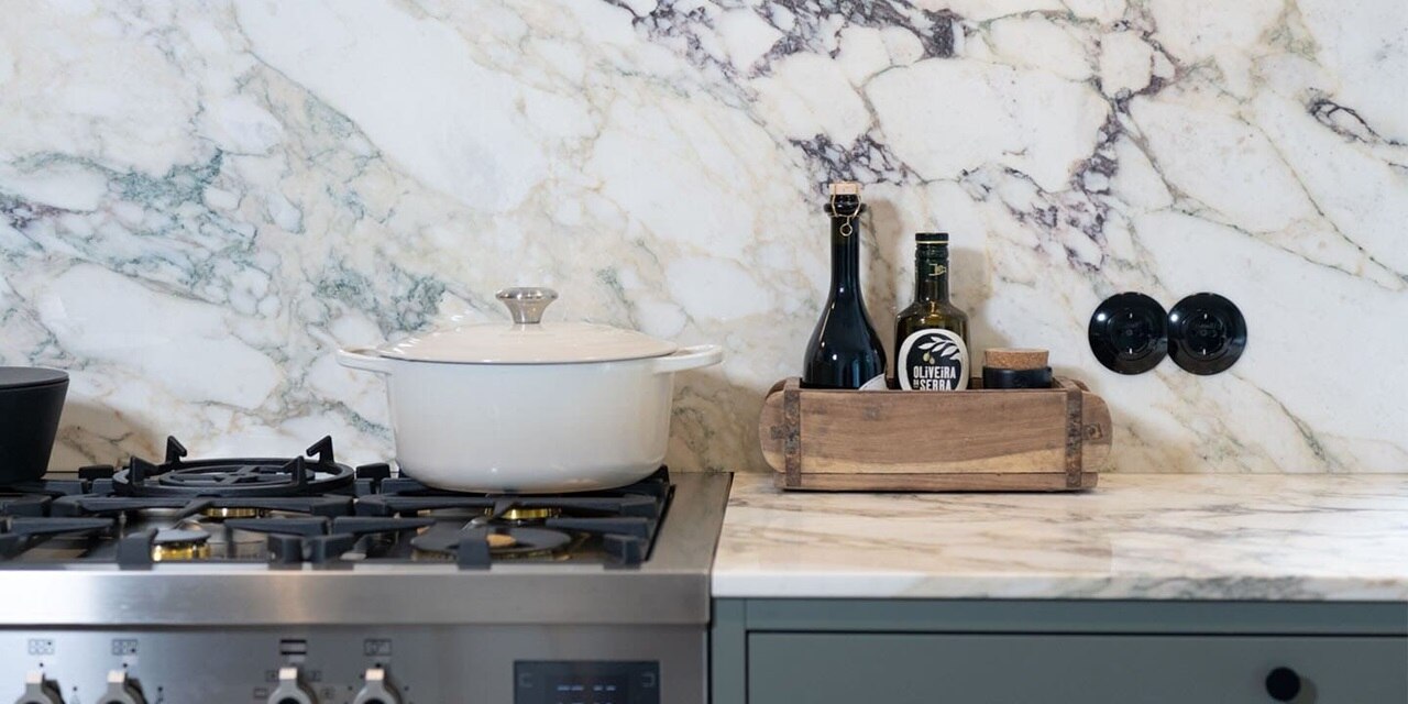 Esempio di installazione di prese Berker Serie 1930 rotonde con placca di copertura nera su parete di cucina con lastre di marmo