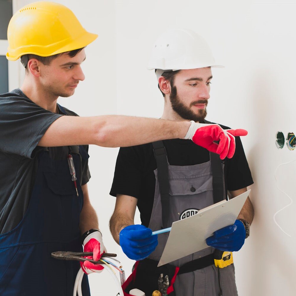 Elettricisti in fase di installazione di prese e interruttori Berker su parete bianca