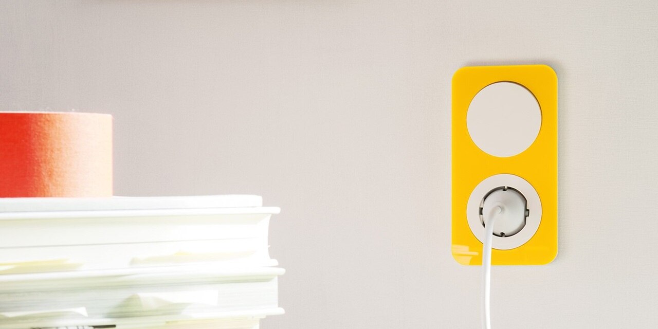 Esempio di installazione di interruttori e prese Berker R.1 con elemento centrale rotondo bianco e cornice arrotondata gialla in acrilico su una parete grigio chiaro