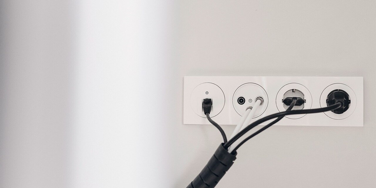 Esempio di installazione di una porta LAN Berker R.3, prese per antenna e prese con elemento centrale rotondo e cornice bianca su una parete grigio chiaro