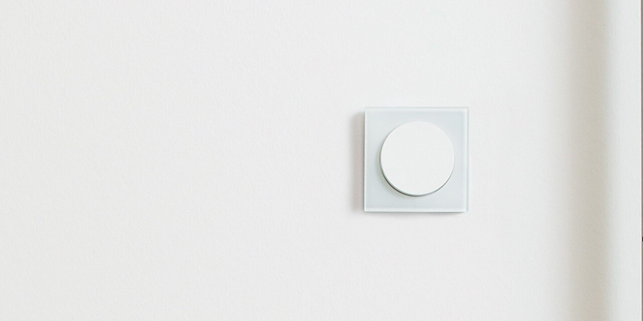 Esempio di installazione dell'interruttore della luce Berker R.3 con elemento centrale rotondo bianco e cornice in vetro su una parete bianca nell'area interna