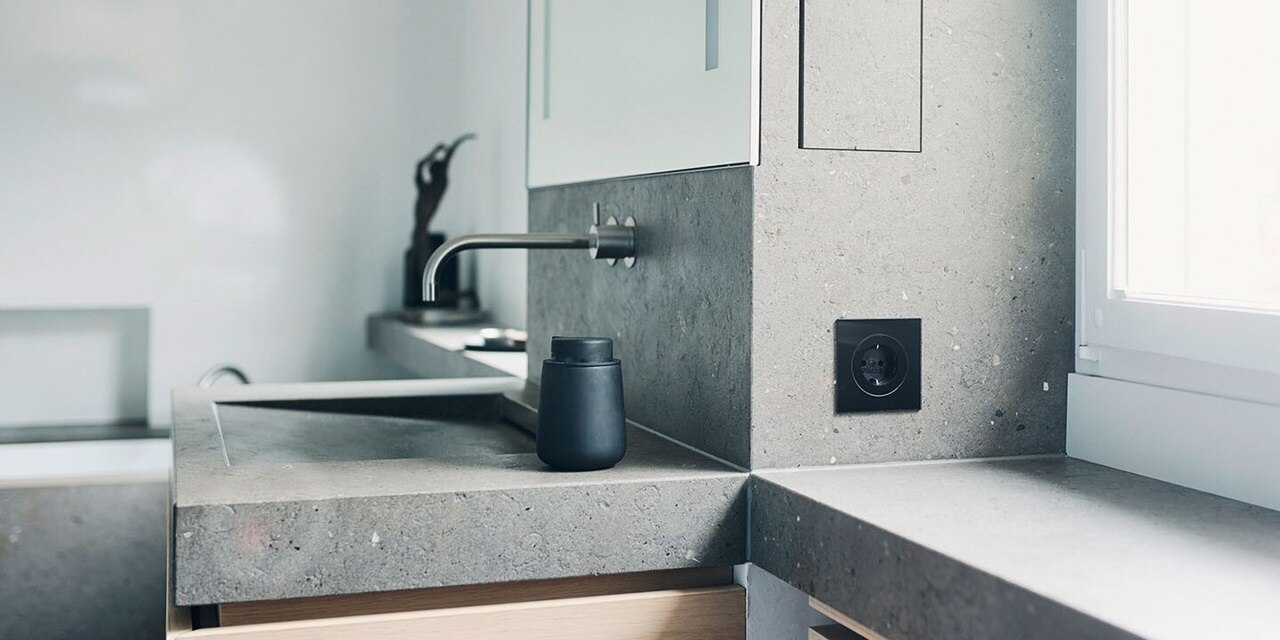 Esempio di installazione di prese Berker R.8 con elemento centrale rotondo e cornice nera su piastrelle in bagno