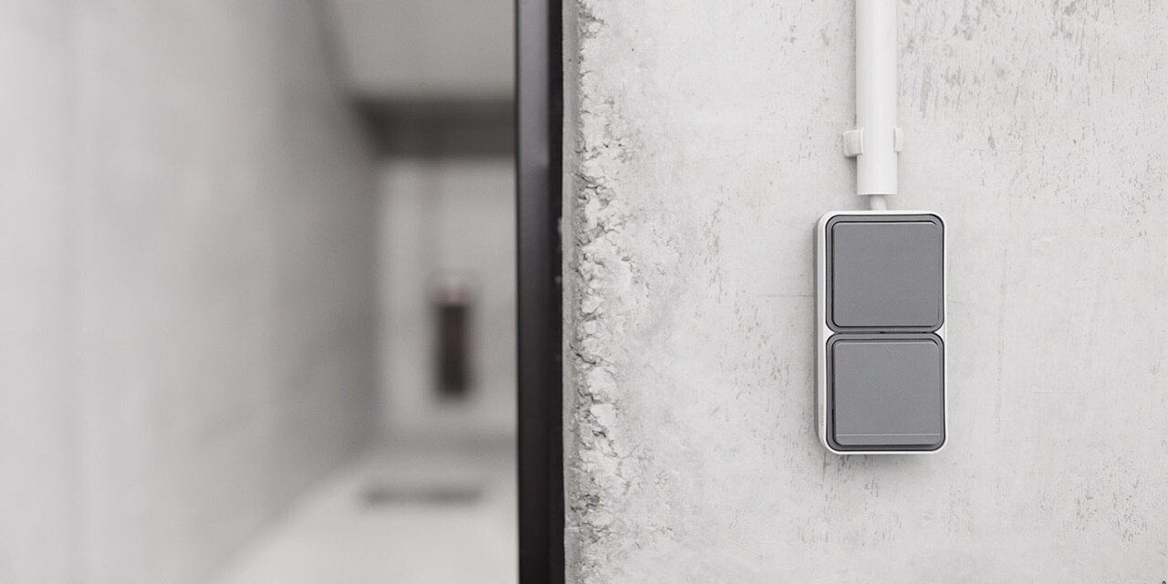 Esempio di installazione di un interruttore doppio Berker W.1 da superficie con bilanciere grigio su una parete in cemento in un corridoio del seminterrato