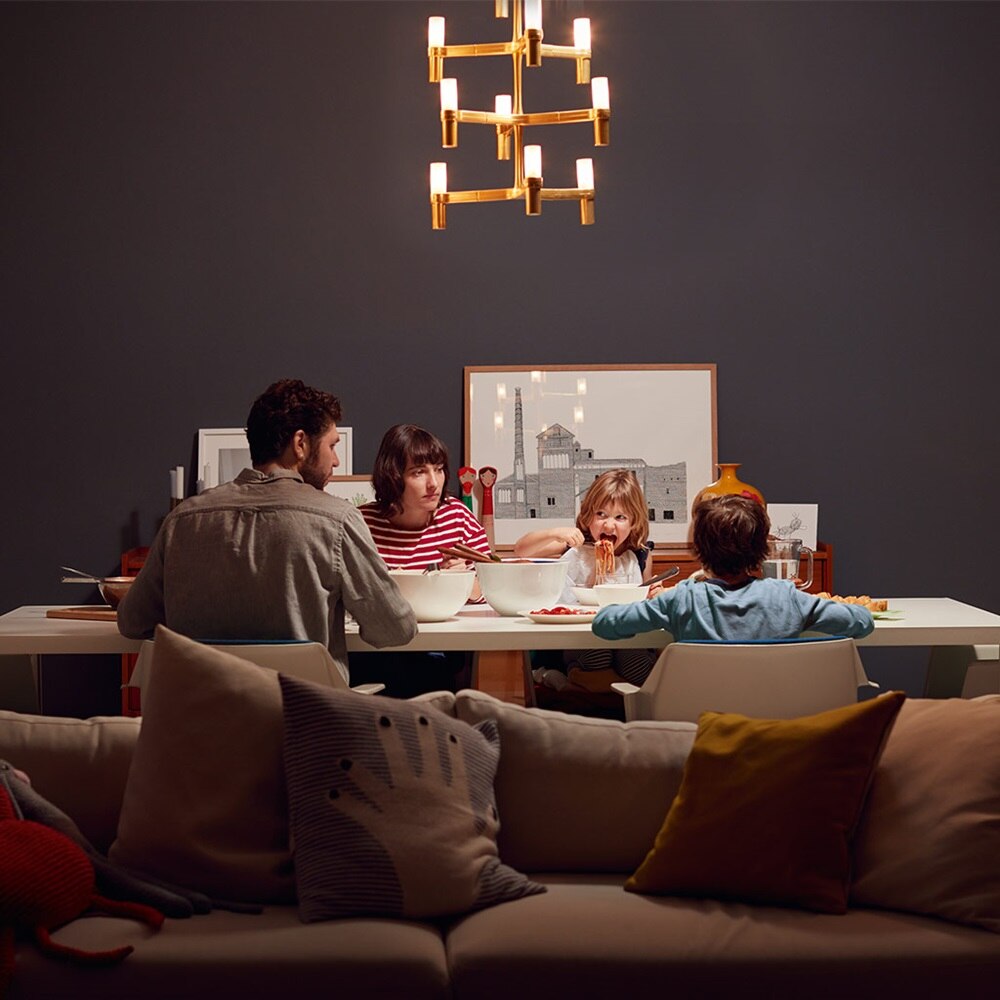 Sala da pranzo illuminata con famiglia di quattro persone a tavola per la cena