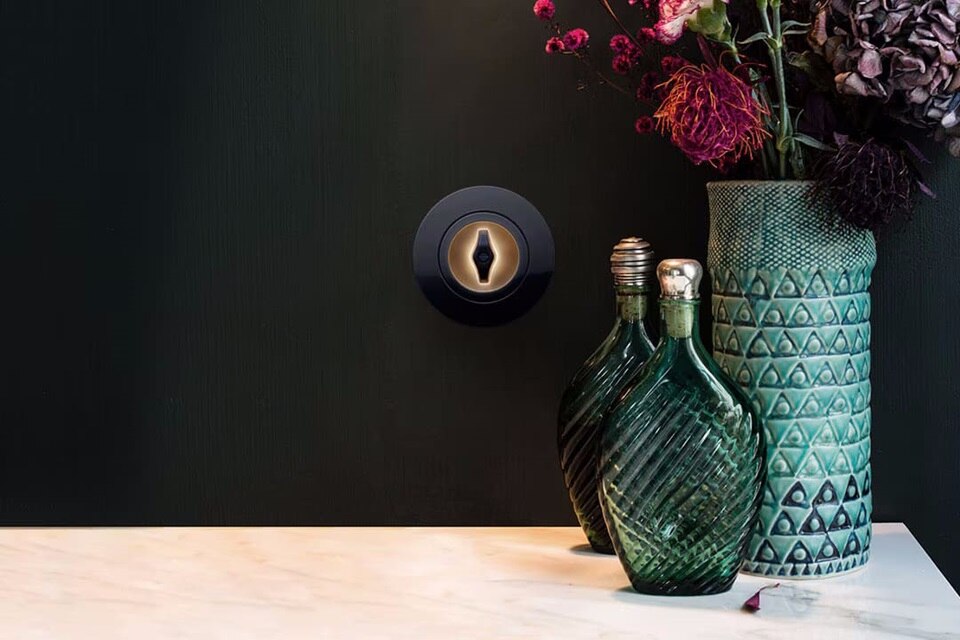 Esempio di installazione di un interruttore della luce retrò Berker Serie 1930 con manopola e illuminazione e cornice di copertura nera su una parete nera