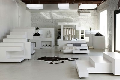 Showroom di abbigliamento con capi esposti su stand e scaffali, in un ambiente ordinato e luminoso