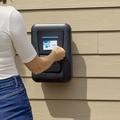 Un installatore utilizza la colonnina di ricarica witty one con cavo, installata nella parete esterna di una casa, avvicinando la carta RFID per attivare la ricarica.