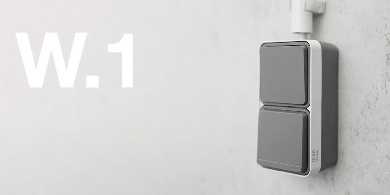 Vista angolata dell'interruttore combinato e della presa in grigio per il montaggio superficiale della gamma di interruttori Berker W.1 per ambienti umidi