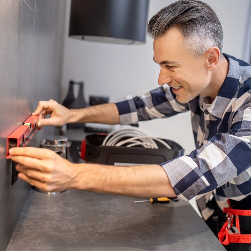 Elettricista intento a montare presa e interruttori sulla parete della cucina