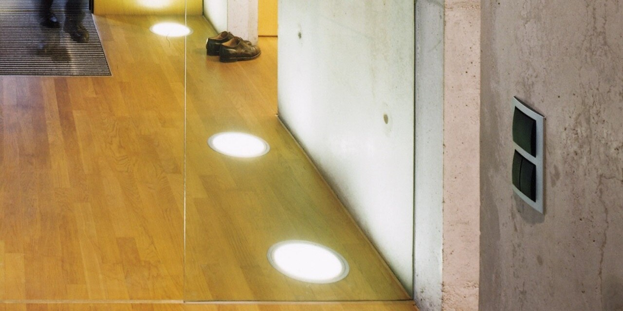 Esempio di installazione dell'interruttore della luce Berker B3 a 1 e 2 vie con bilanciere nero e interruttore cieco nero e cornice a due moduli di colore argento su parete in cemento a vista in interni