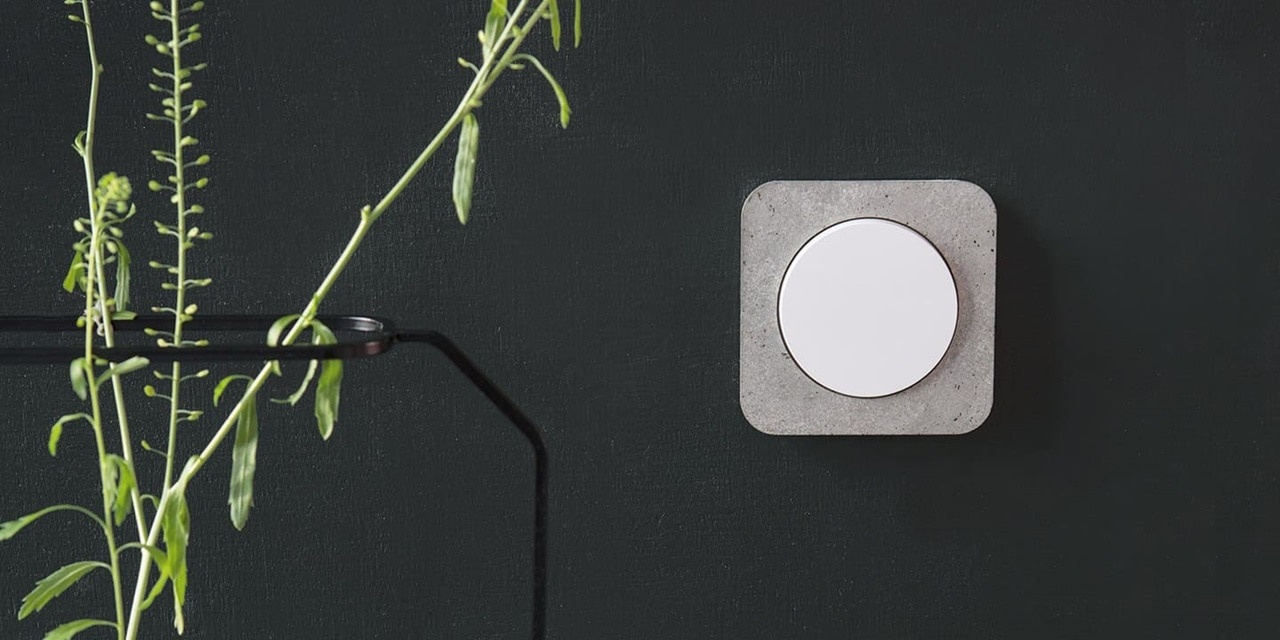 Esempio di installazione dell'interruttore della luce Berker R.1 con parte centrale rotonda in bianco e cornice arrotondata in cemento su una parete nera in un interno