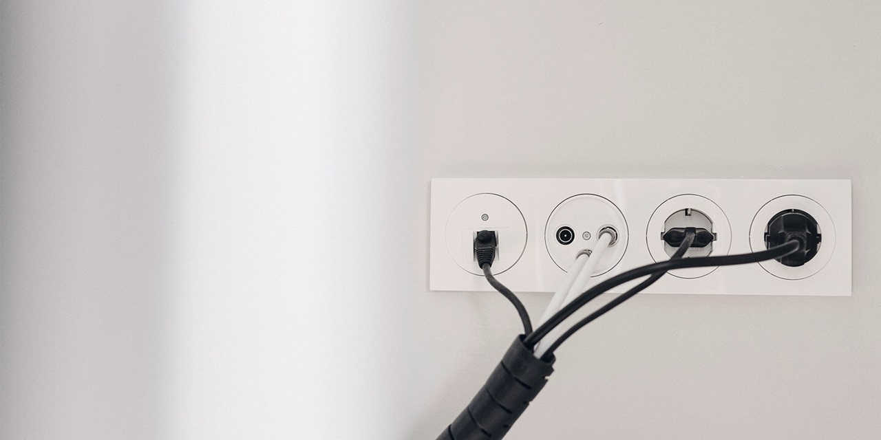 Esempio di installazione di una porta LAN Berker R.3, prese per antenna e prese con elemento centrale rotondo e cornice bianca su una parete grigio chiaro