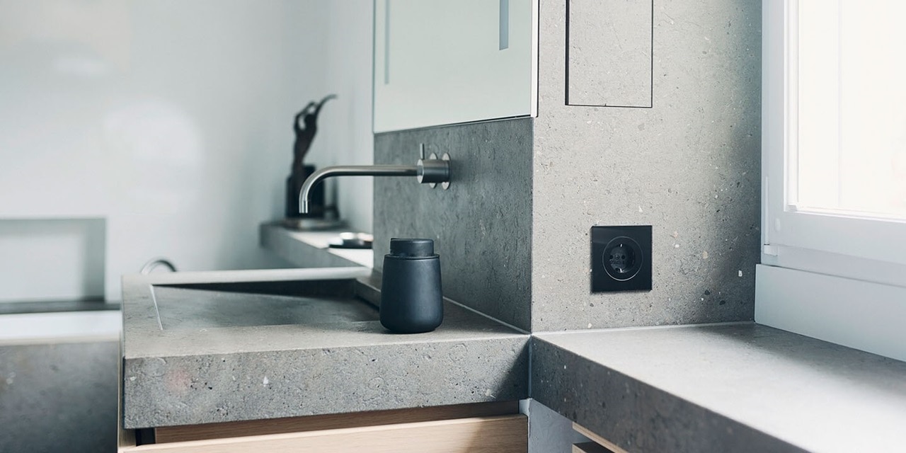 Esempio di installazione di prese Berker R.8 con elemento centrale rotondo e cornice nera su piastrelle in bagno