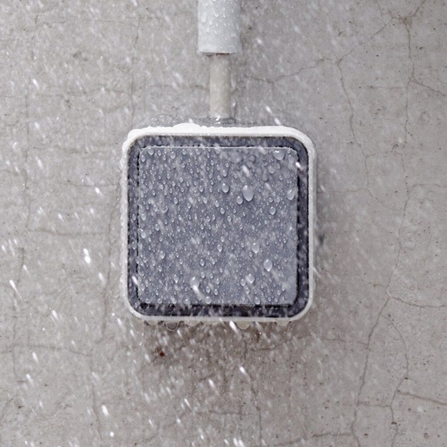 Esempio di installazione dell'interruttore Berker W.1 con bilanciere grigio montato su un muro di cemento sotto la pioggia, vista frontale