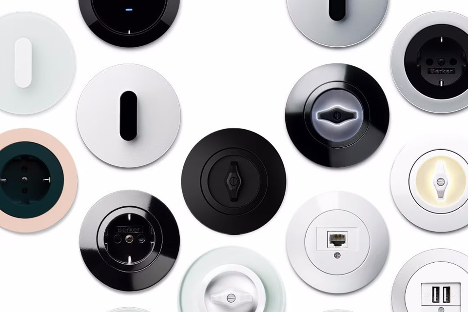 Panoramica frontale di diverse varianti di interruttori e prese Berker di forma rotonda e colori, su sfondo bianco