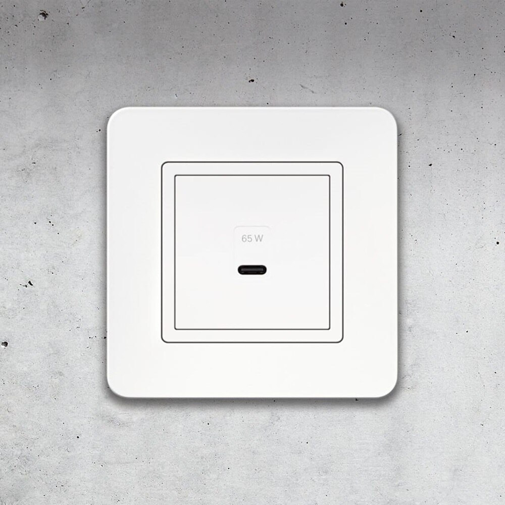 Vista frontale della presa di ricarica USB-C Berker Q.7 con cornice bianca e sfondo in cemento