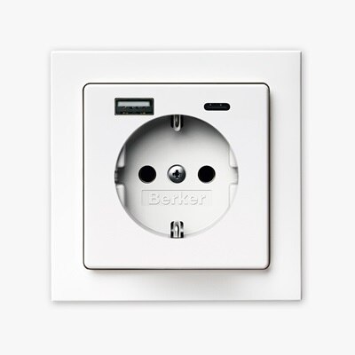 Vista frontale della presa tipo shuko Berker Q.3 con due porte di ricarica USB, una USB-A e una USB-C, e cornice bianca su sfondo neutro