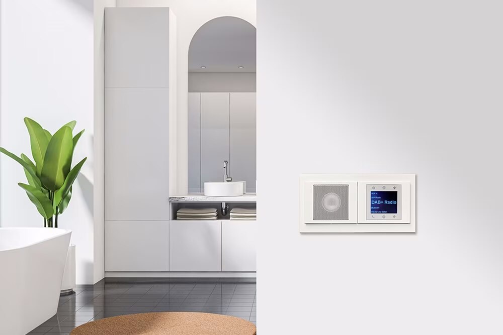 Esempio di installazione di una radio Berker da incasso con display, comandi e altoparlante con cornice bianca su una parete bianca in un bagno