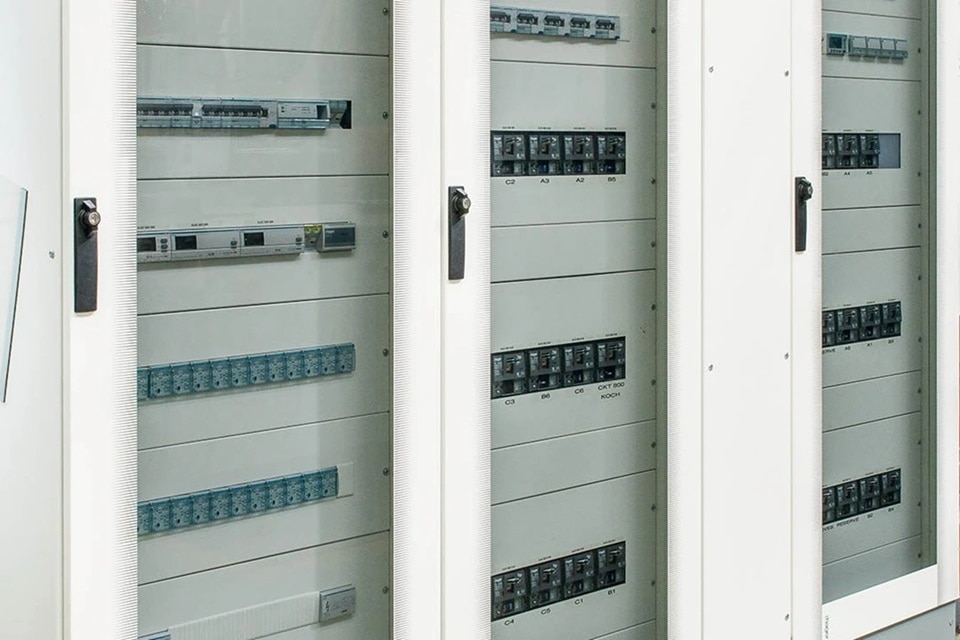 Electrical distribution board with multiple circuit breakers inside a white cabinet