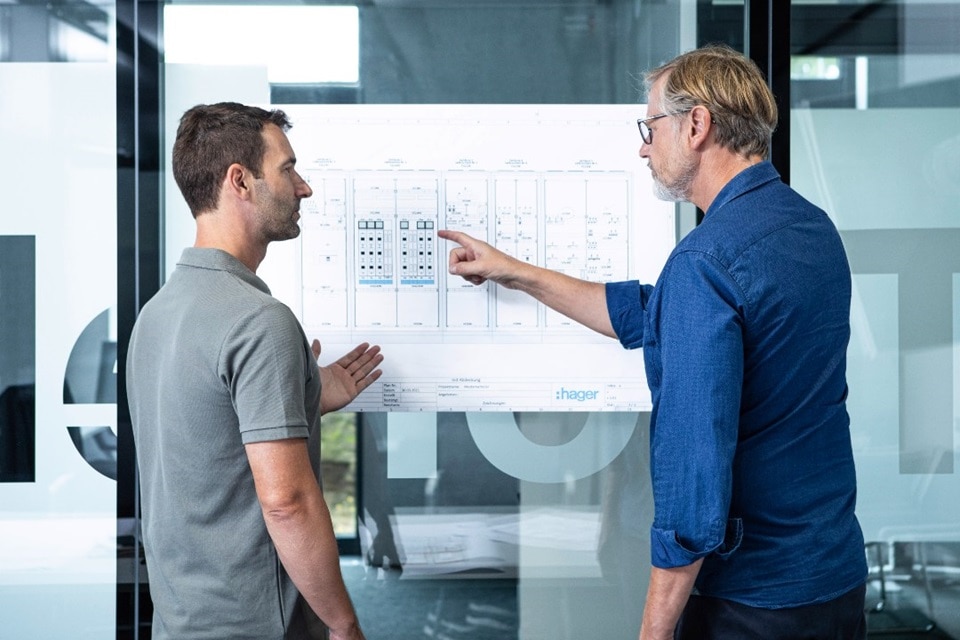 Two professionals discussing over electrical distribution schematics in office
